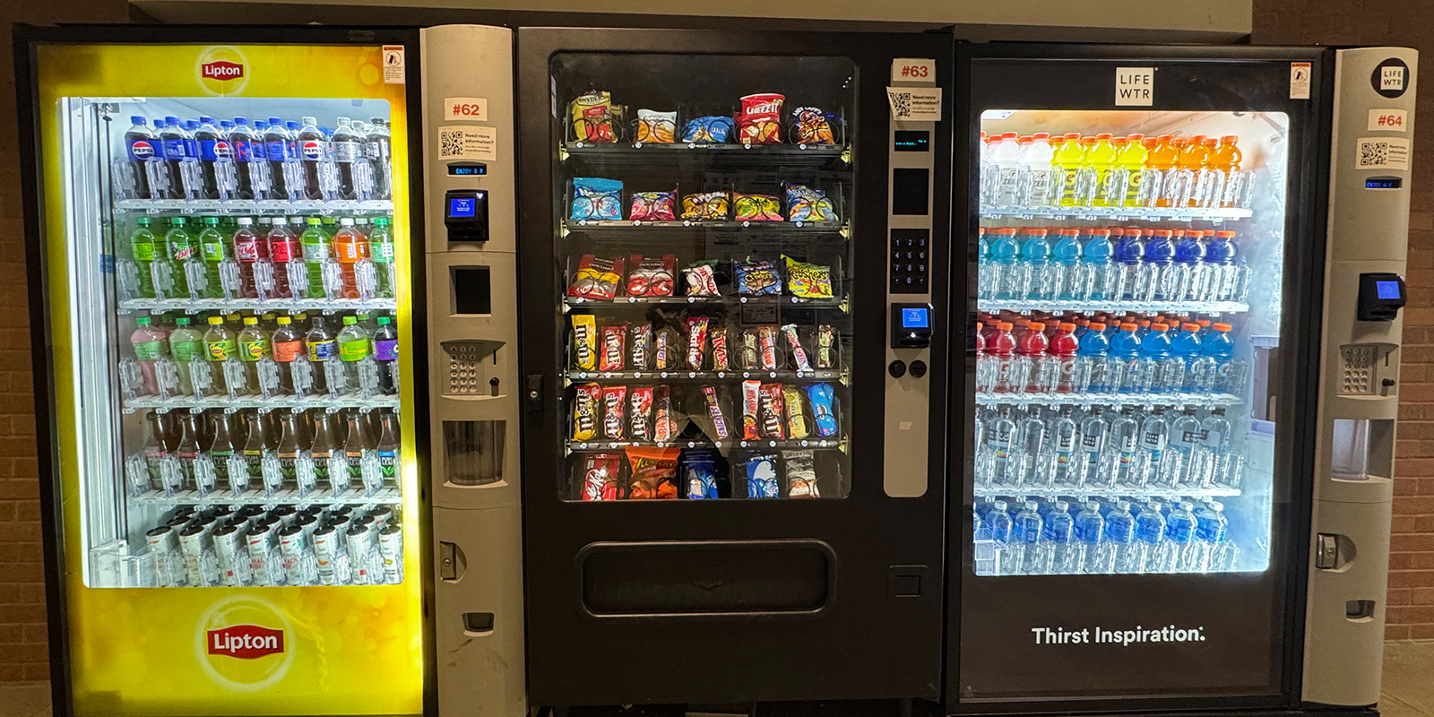 ﻿Three vending machines: left with Lipton and beverages, center with snacks like chips and candy bars, right with bottled water and drinks