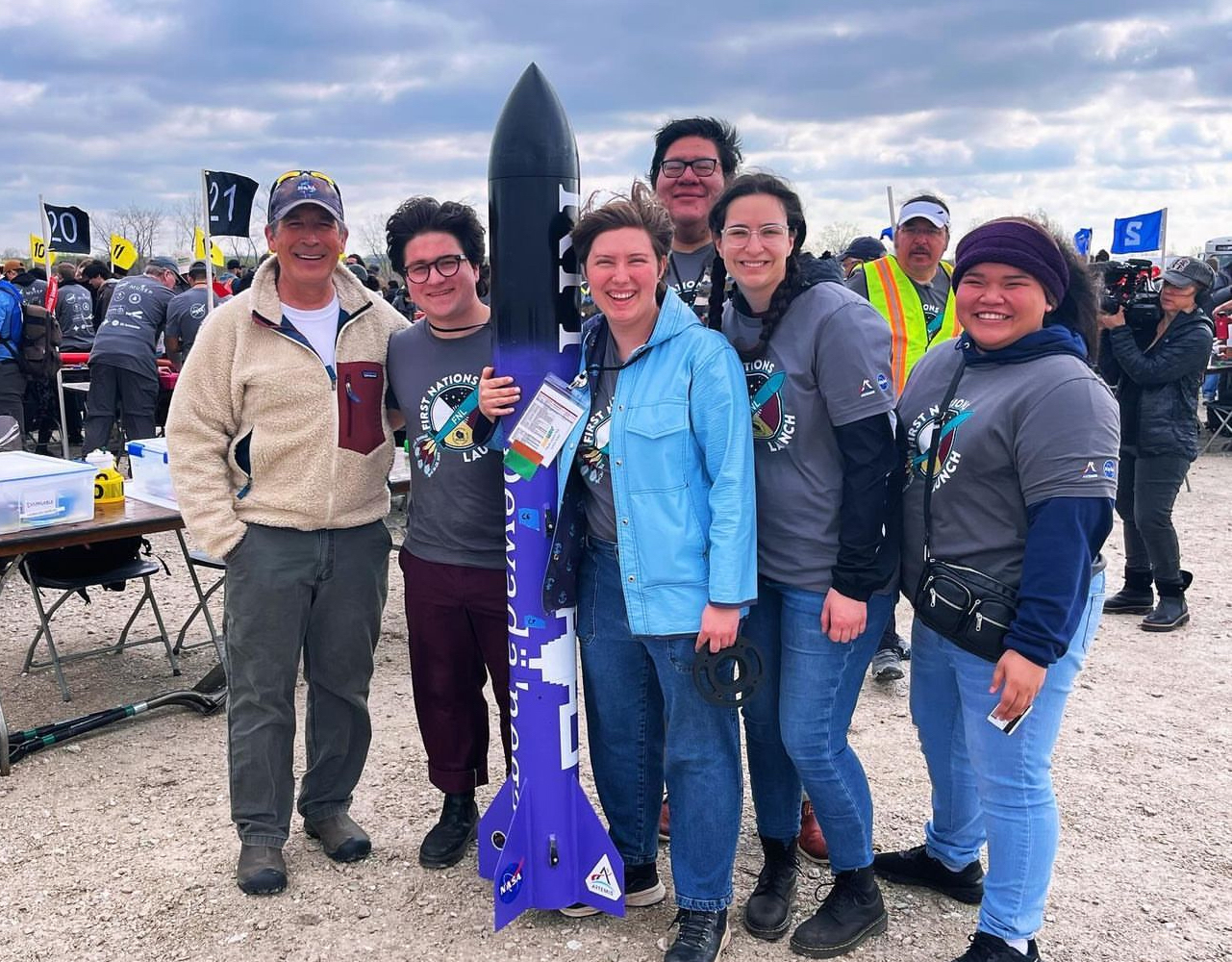 group of people standing outside with rocket