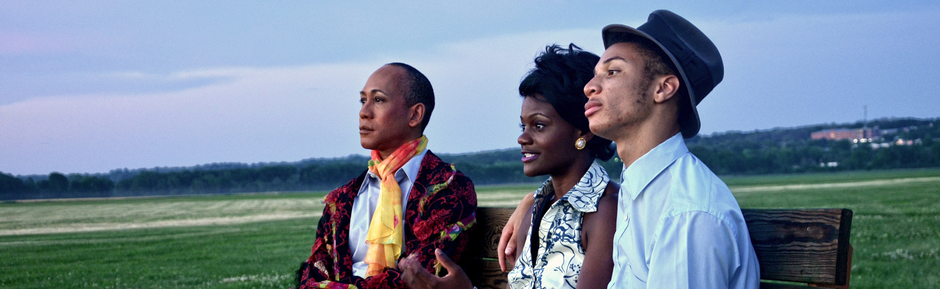 three people sitting on bench at sunset