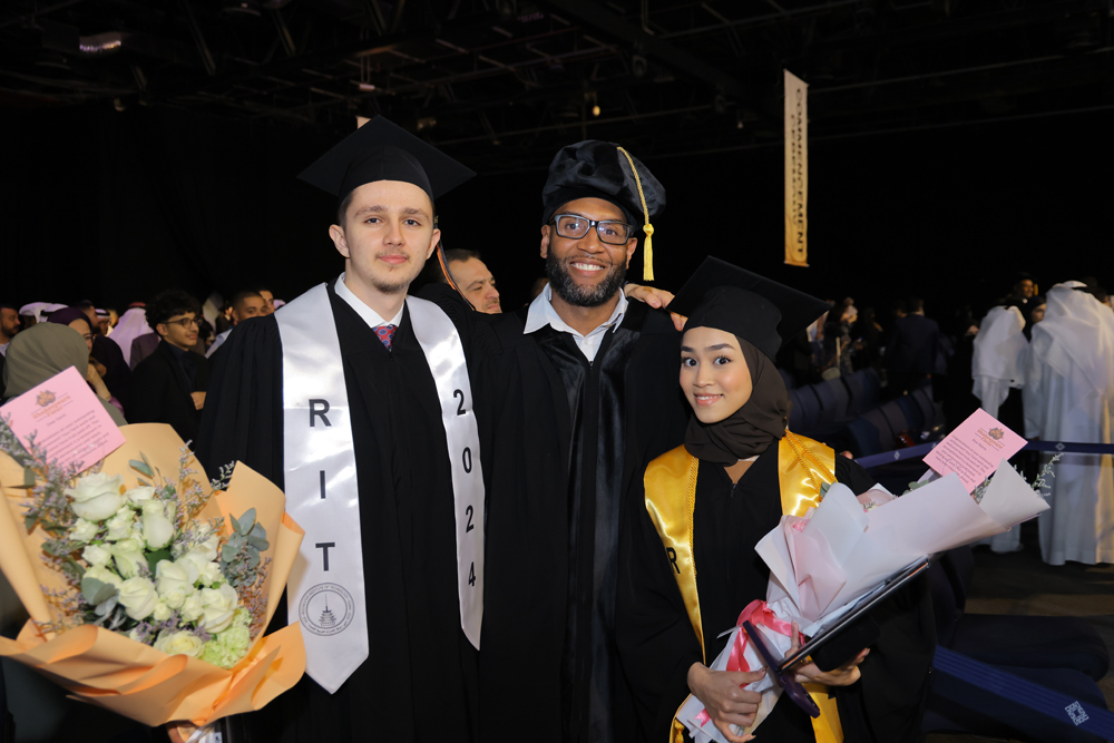 RIT graduates posing with a professor