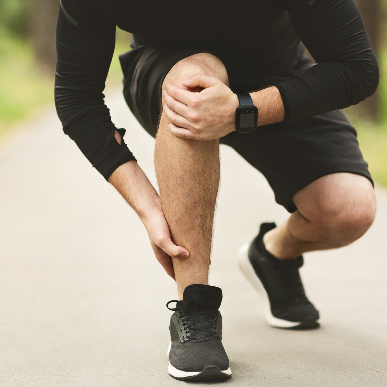 runner checking leg while wearing electronic device