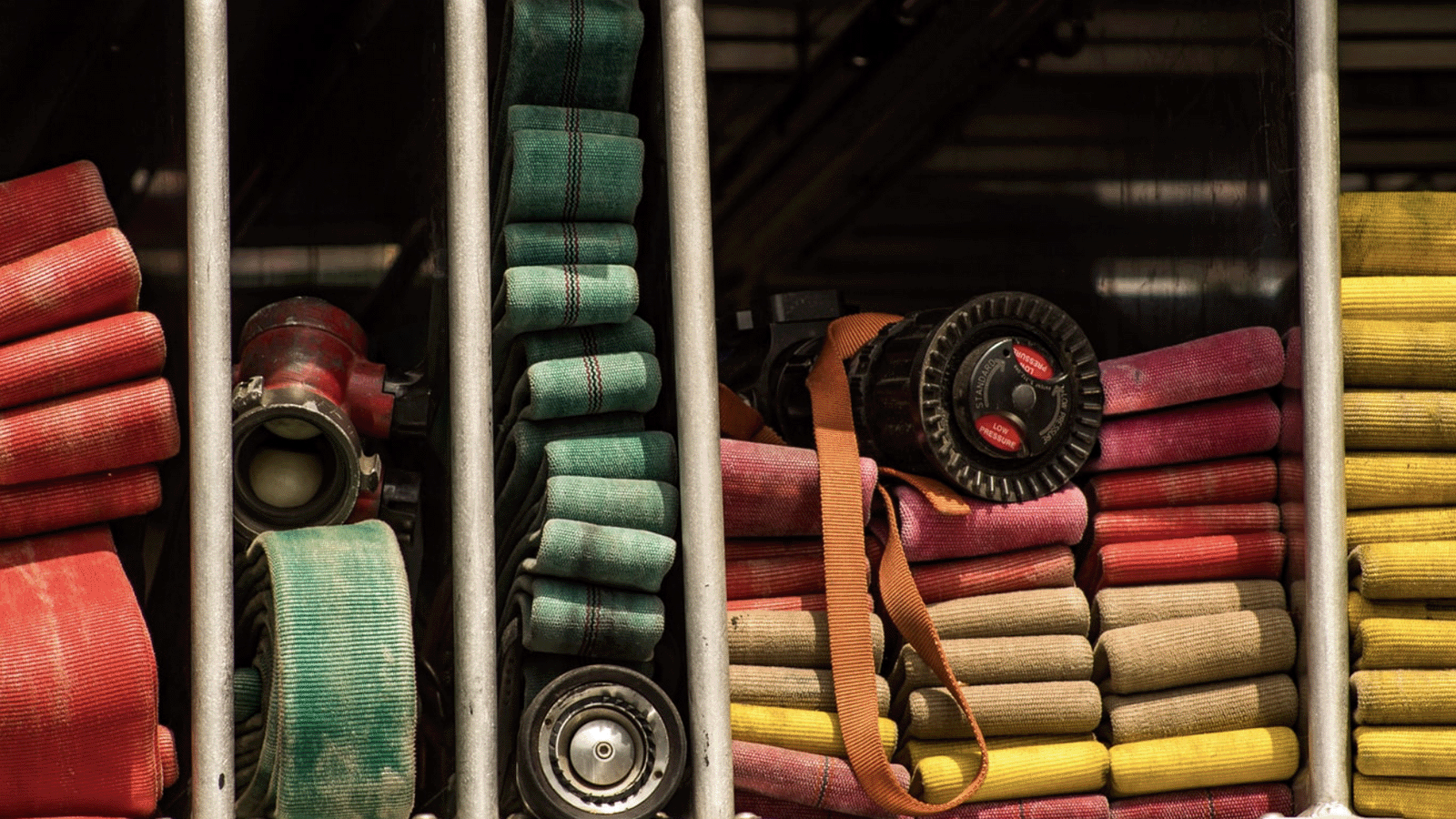 A collection of tightly packed, colorful fire hoses stored on a rack.