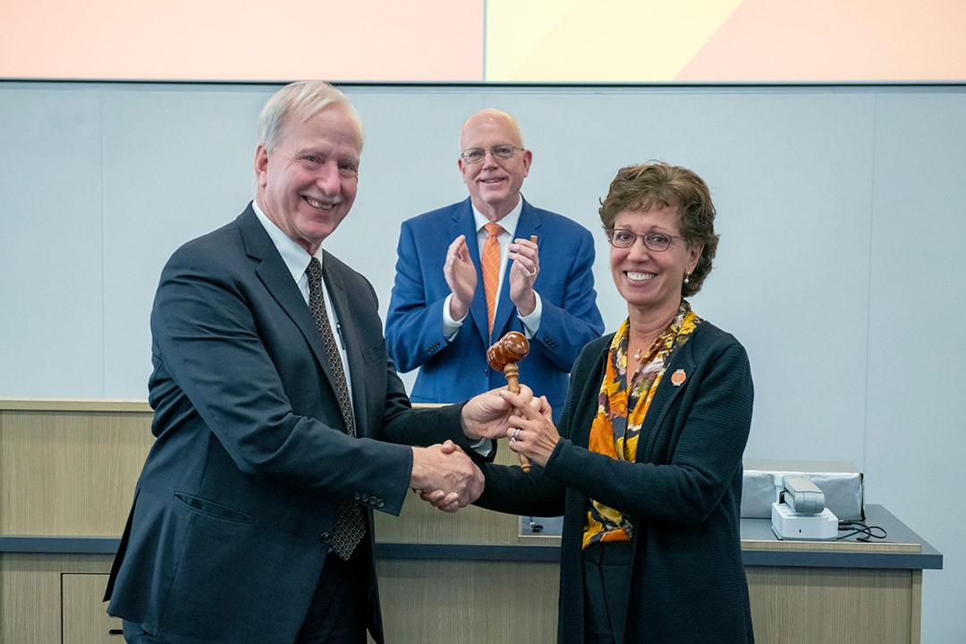 Outgoing chairperson of RIT’s Board of Trustees Jeffrey Harris ’75, left, hands the gavel to incoming chairperson Susan Puglia as President David Munson looks on.