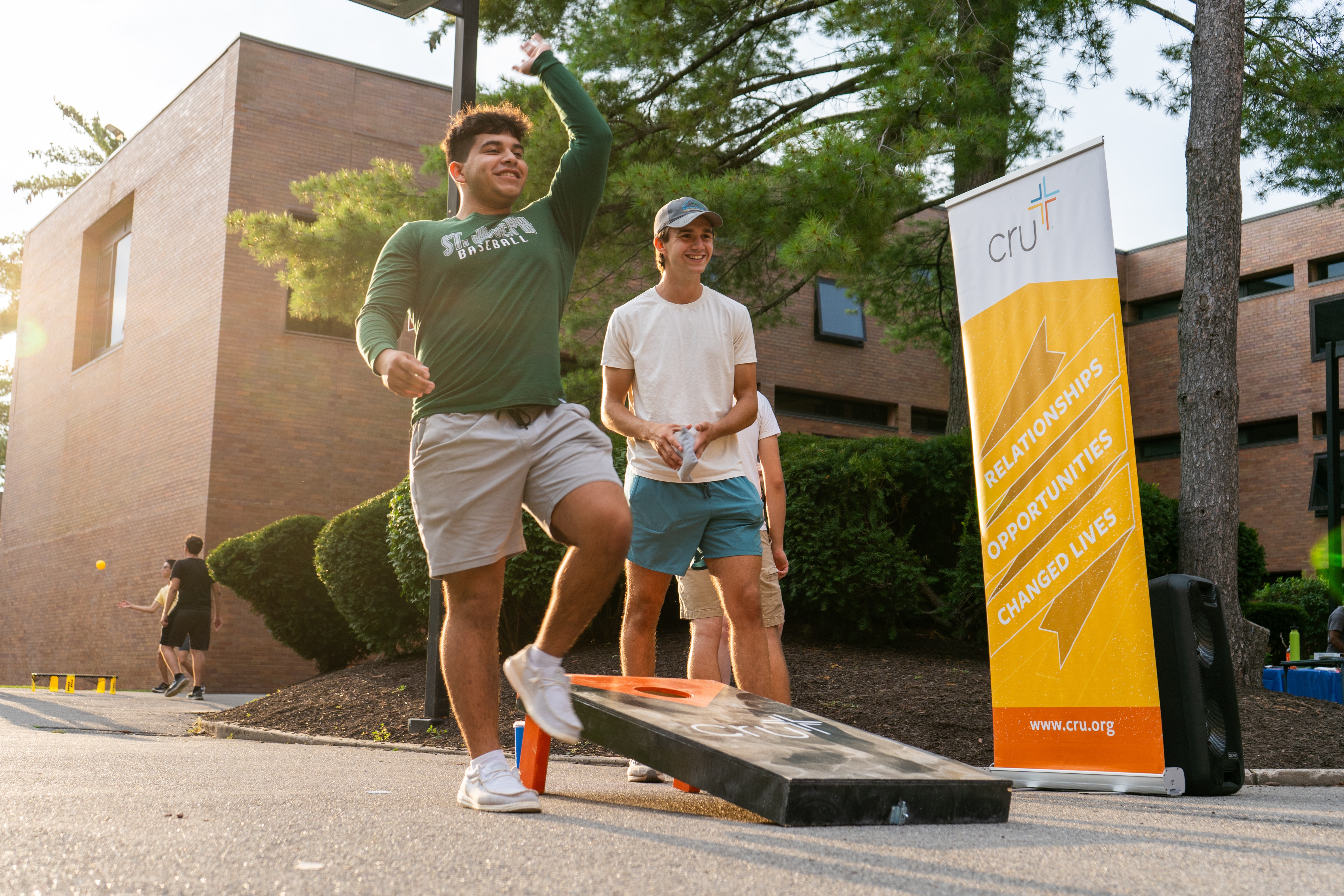 Two students playing corn hole outside of the residence halls
