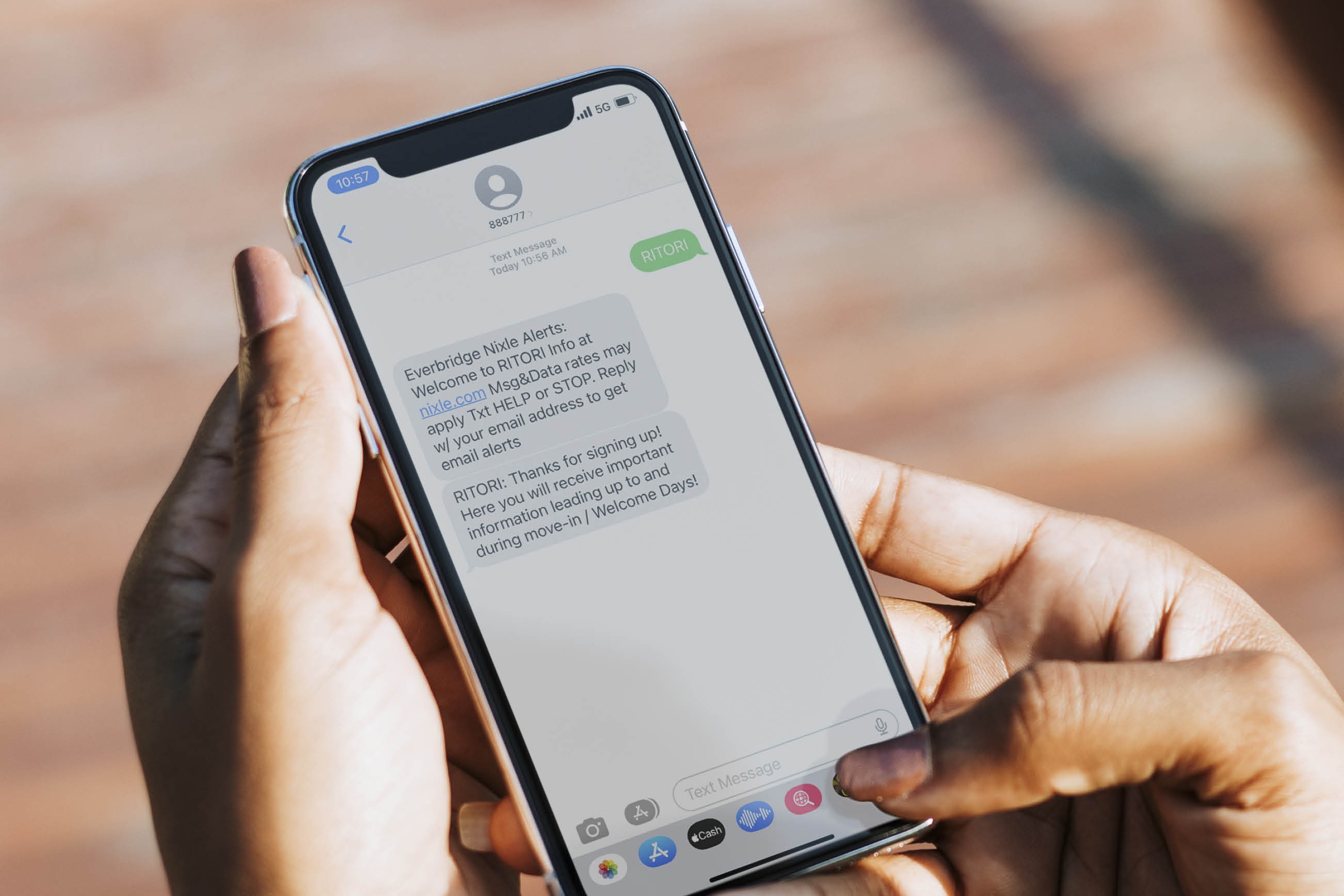 A hand holds a iPhone displaying a text message thread.