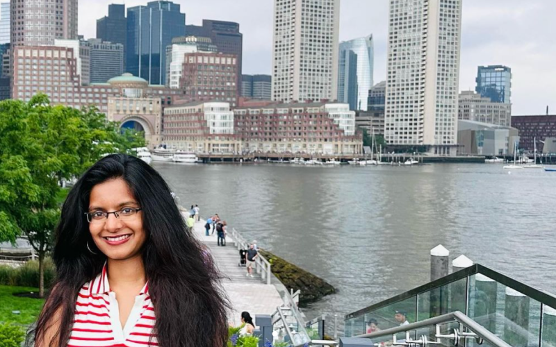 A young woman standing in front of a cityscape.