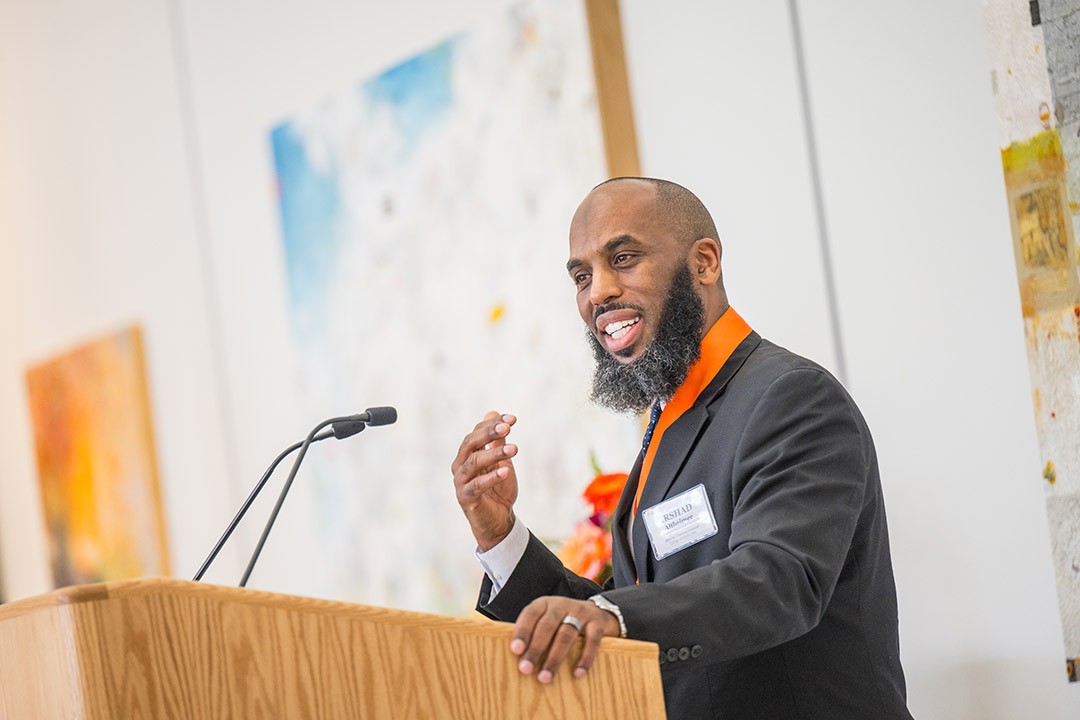 A man giving a speech at a podium in a bright room.