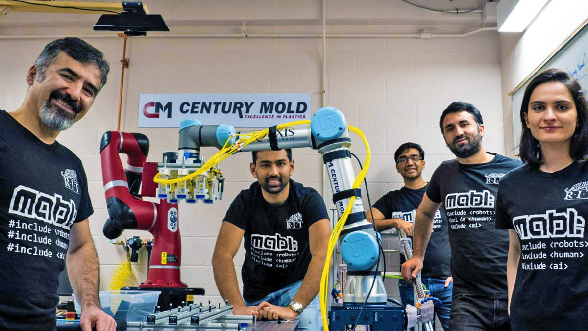 A group shot of people surrounding a robotic arm labeled Century Mold.