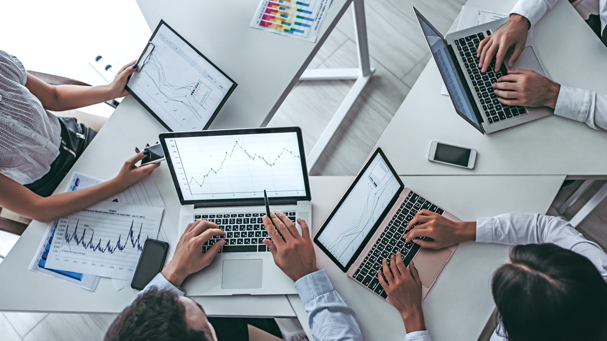 Top-down photo of laptops with hands typing on the keyboards.