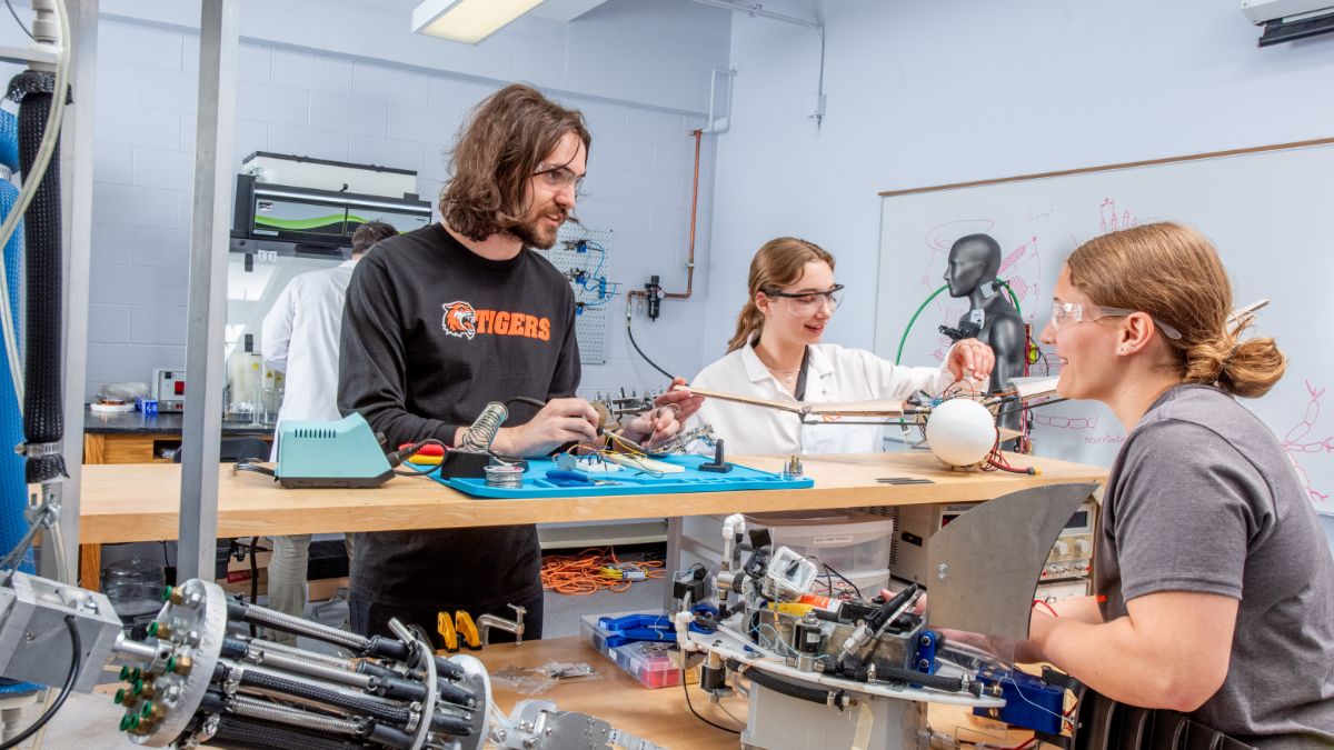 Students work in a lab, one wearing an RIT Tigers long-sleeve shirt.