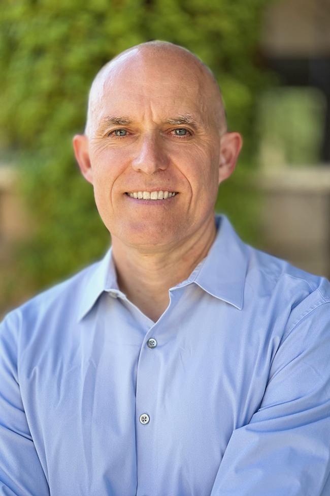 A headshot of Hans Laudon wearing a light blue button down shirt.