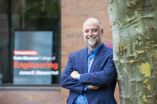 Department Head of Mechanical Engineering at RIT, Byron Erath, leaning up against a tree and wearing a blue plaid sports coat.