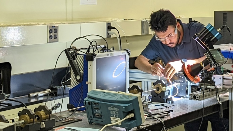 A Ph.D. student wearing safety glasses and working in an engineering lab.