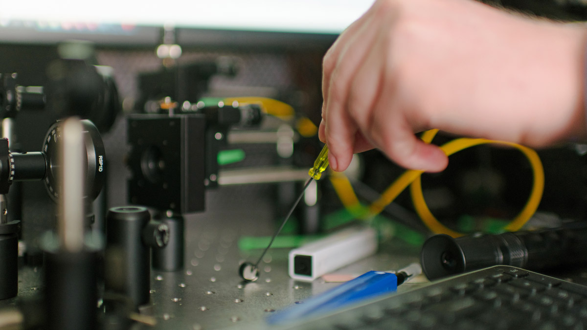 Close up of hand working on circuit board.