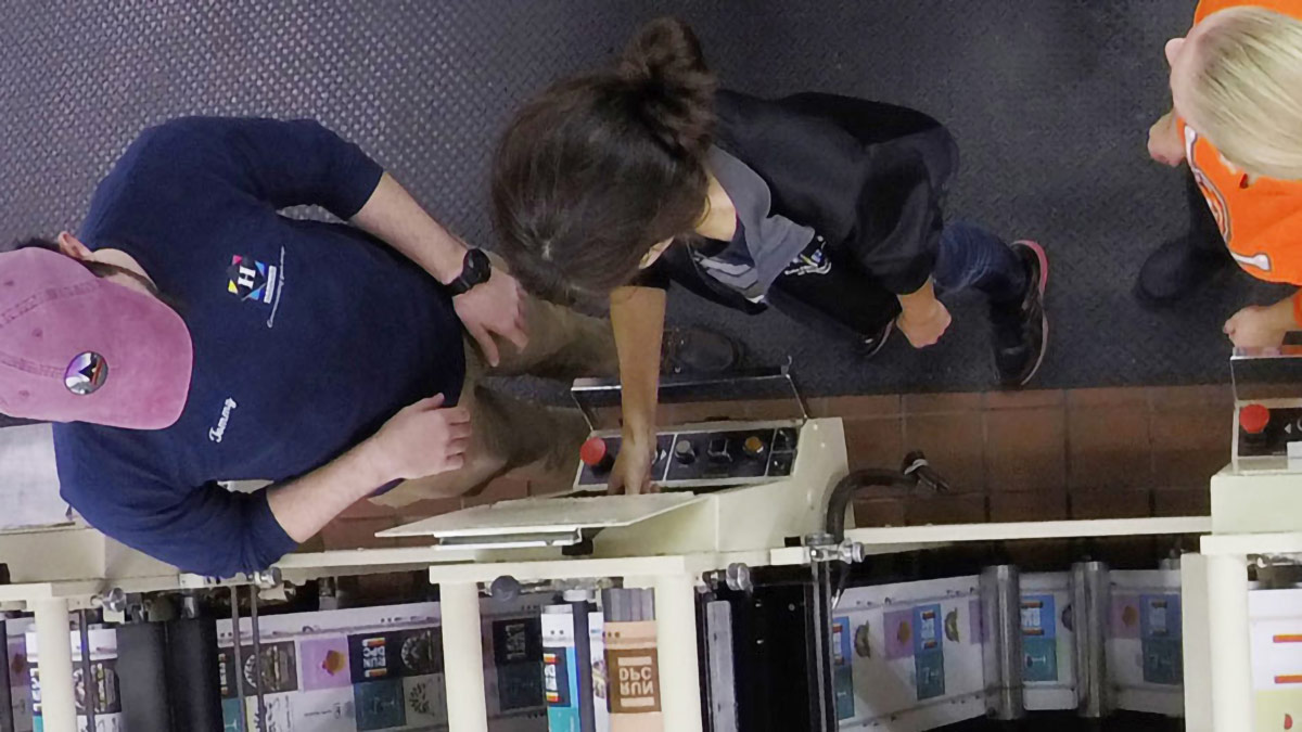 Top down photo of students working with a printing press.