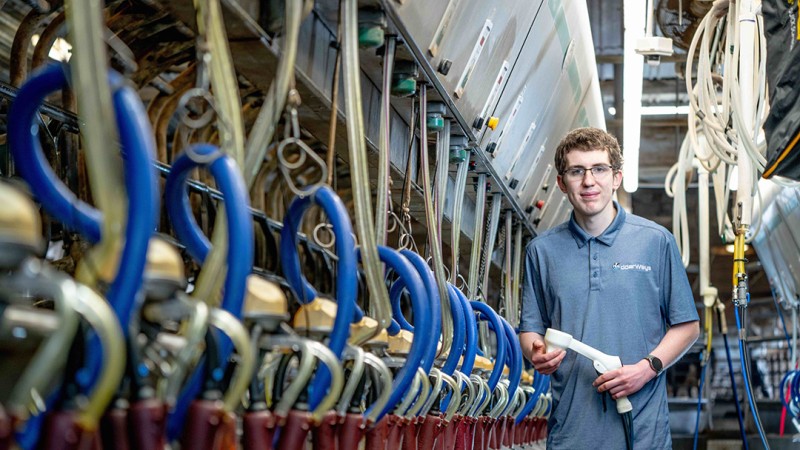Jayden Neal stands next to dairy processing equipment in a barn on his family' farm.