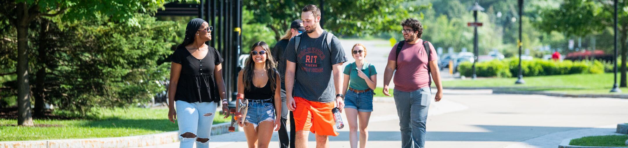 A group of students walking on one of the walkways of the R I T campus.