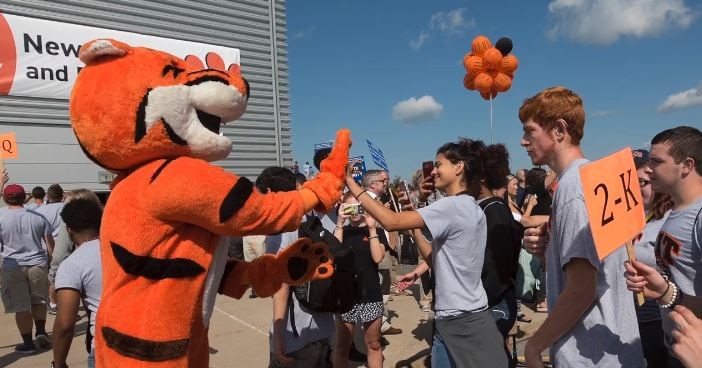 Ritchie the Tiger (mascot) extends a high-five welcoming a student. 