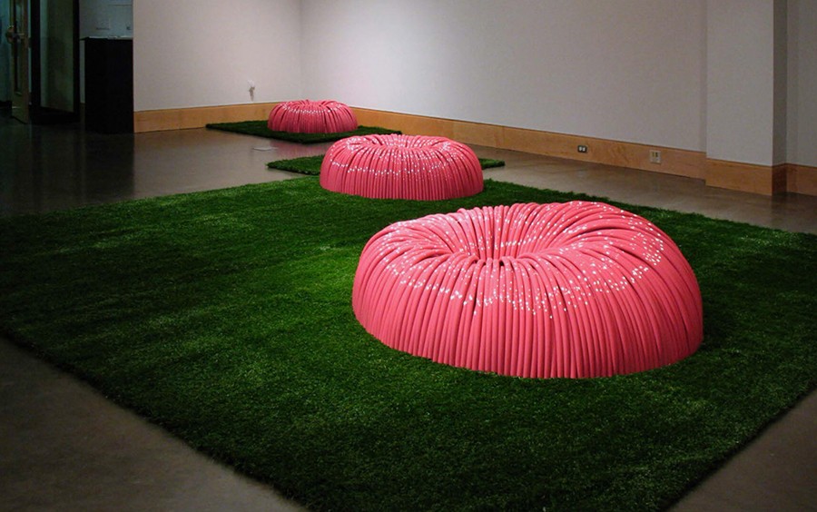 A pink, abstract installation sits in a gallery setting.