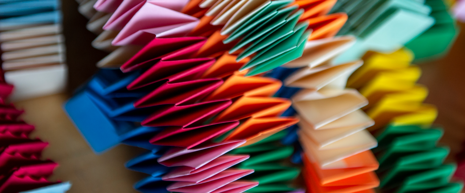  A close-up of a collection of colorful paper in various shades of pink, green, and orange, showcasing a creative and vibrant display of simple origami.