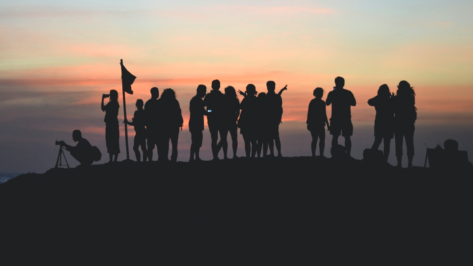 Silhouette of friends watching the sunset from a mountaintop