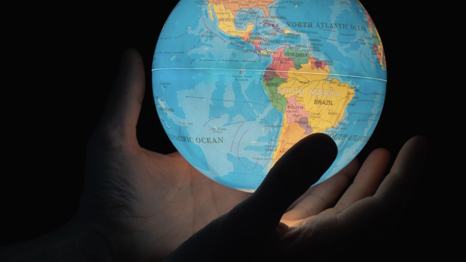 Silhouette of hands holding a glowing globe