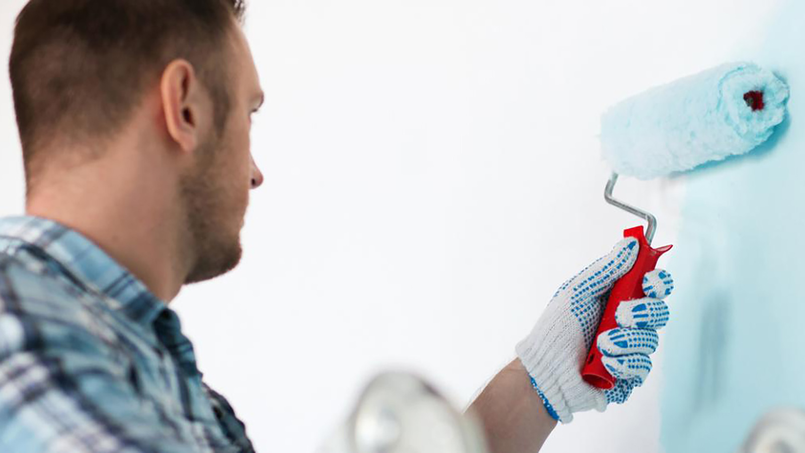 A man painting a wall with a paint roller