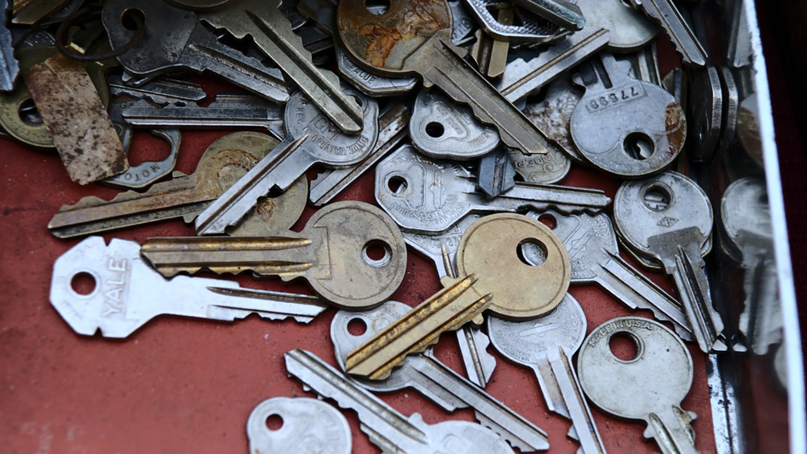 A collection of various keys in different shapes and sizes, scattered and overlapping each other, with some keys appearing worn and tarnished while others look relatively new.