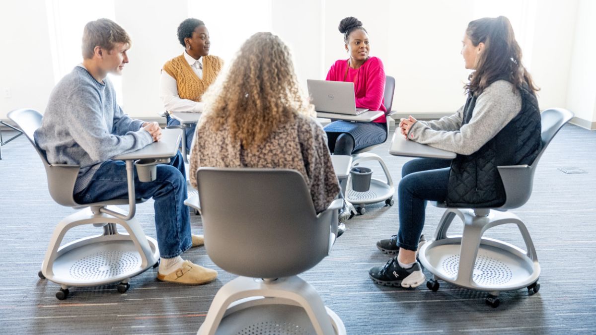 Students seated in a collaborative study space with modern furniture and laptops.