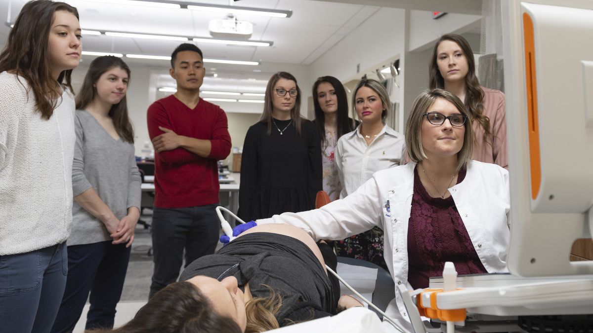 A group of students observing an instructor demonstrating an ultrasound procedure.