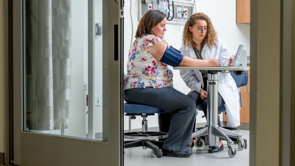 A medical student measuring a patient's blood pressure in a clinic.