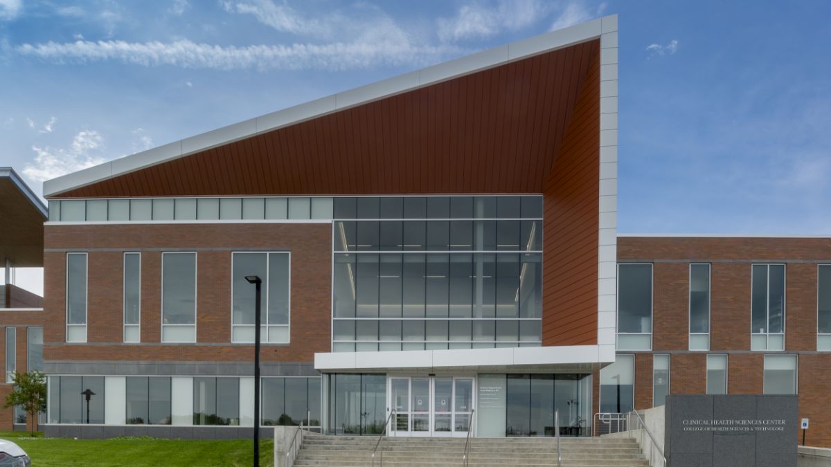 A modern academic building with large windows and a unique triangular roof design.