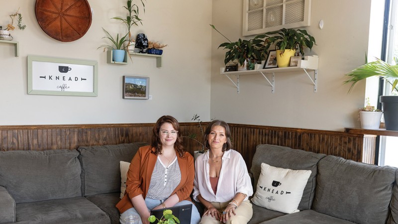 Two ultrasound alumni sit on a coach in a living room.