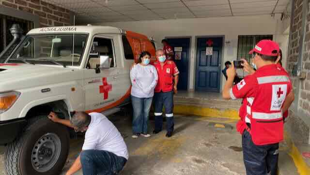 two hospital workers stand in front of ambulance