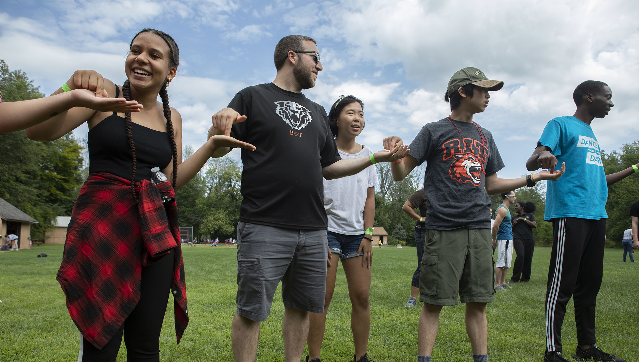 students and a residence life staff member stand hand in hand while smiling