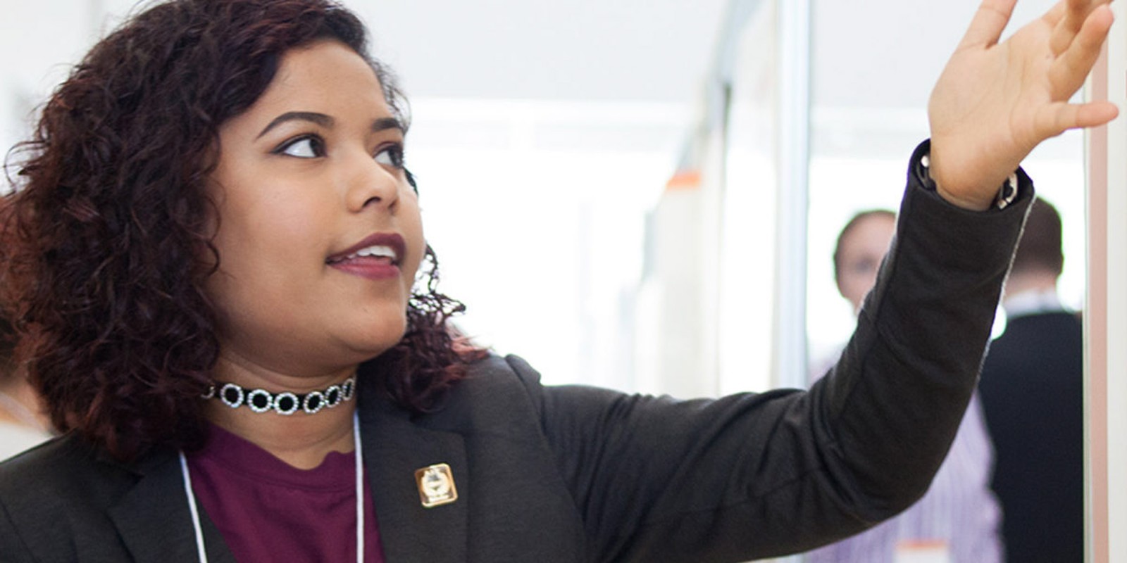 ﻿A woman in an office pointing to a whiteboard, engaged in a discussion or presentation