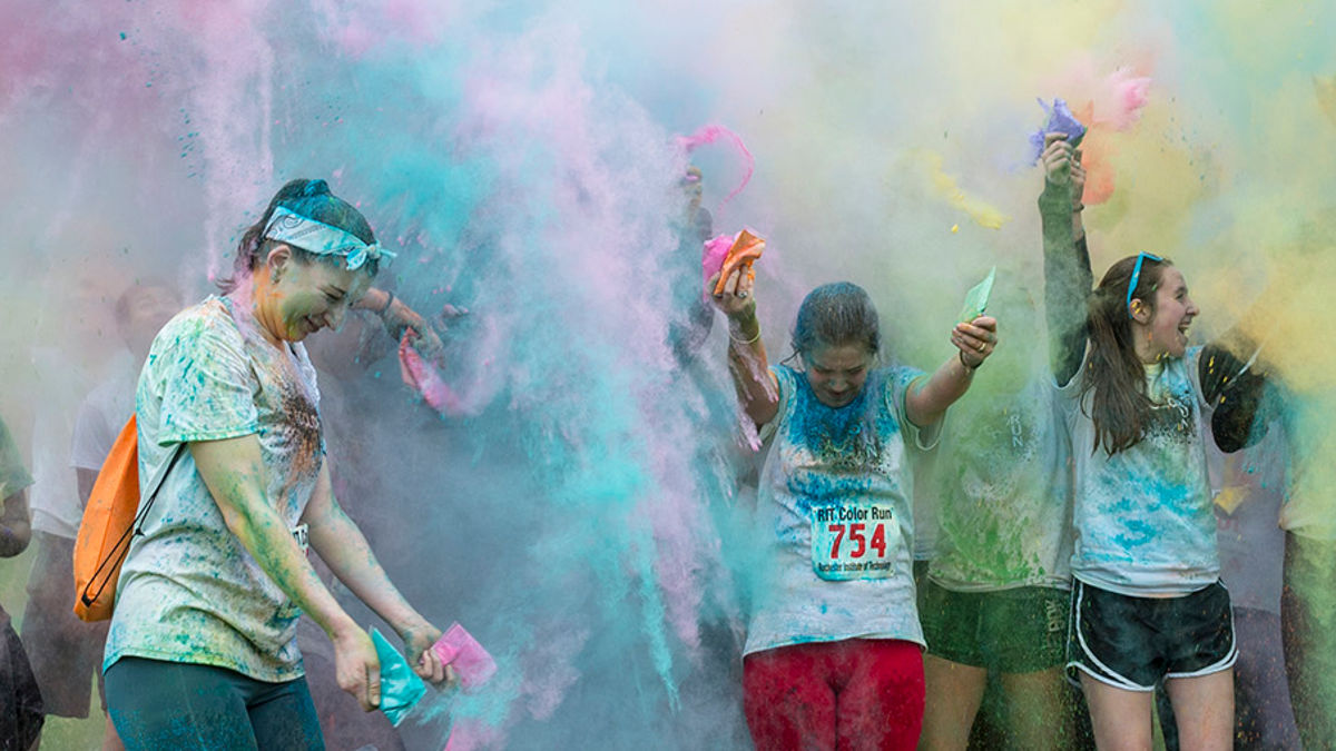 A vibrant color run event with students covered in colorful powders, celebrating fitness and fun in a lively atmosphere.