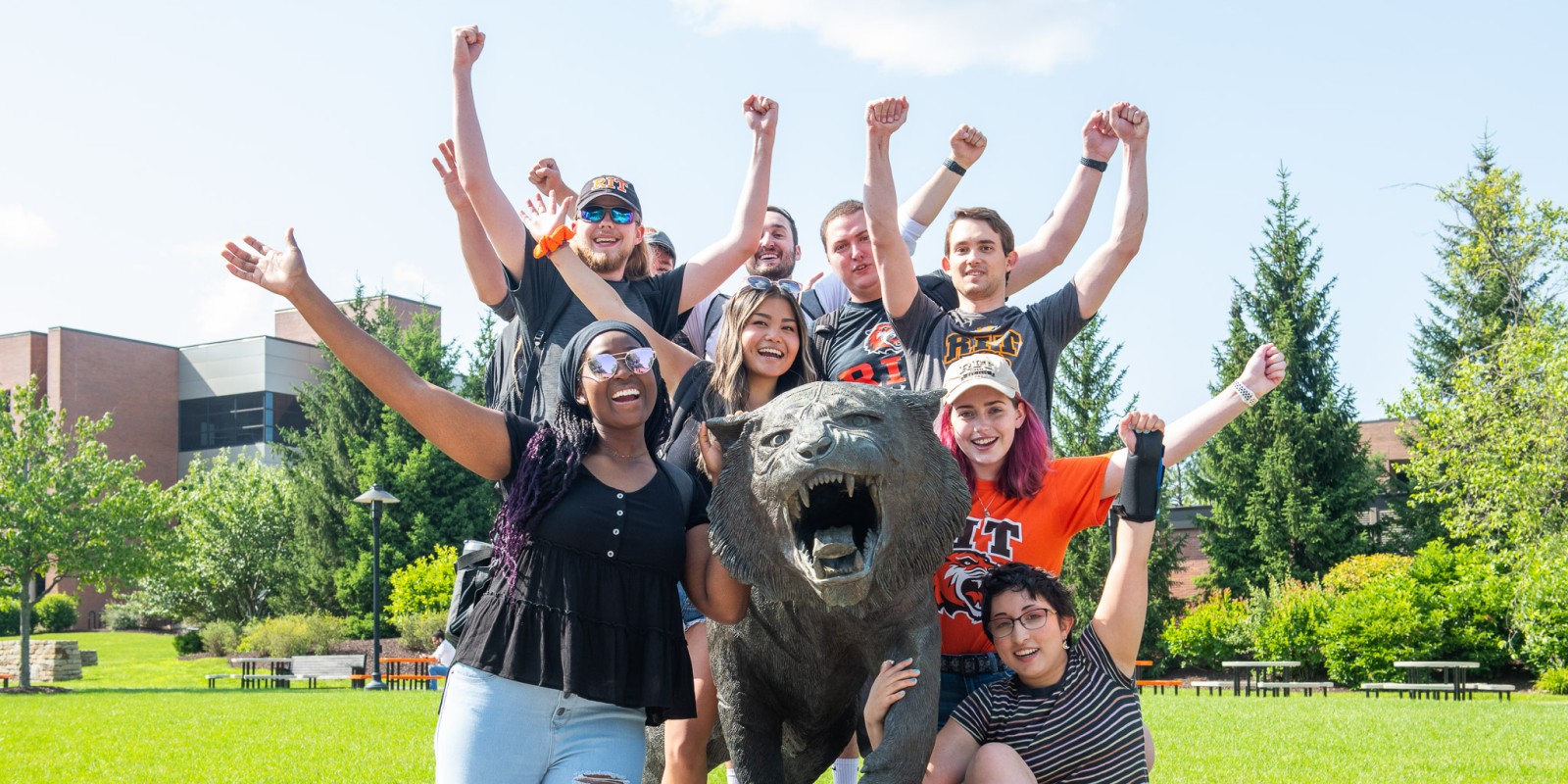 ﻿A diverse group of students gathered around the tiger statue with hands raised and facial expressions of excitement