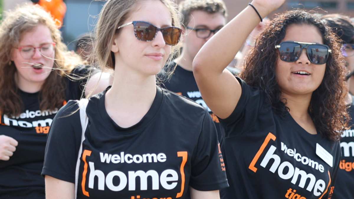 A group of student wearing welcome home t-shirts, smiling and celebrating together in a joyful atmosphere.