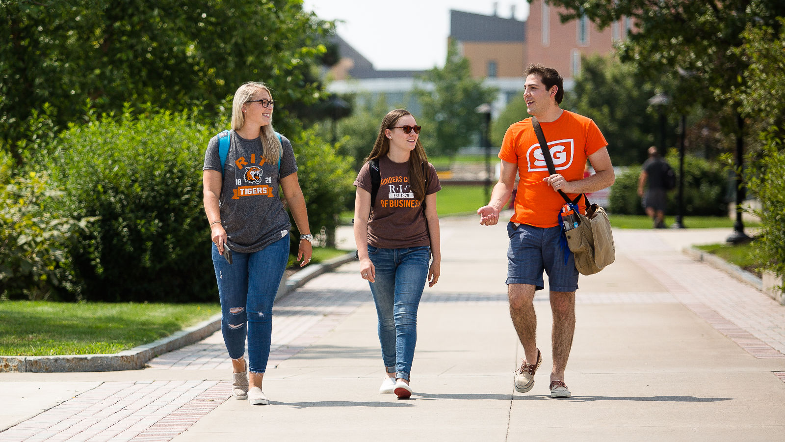 3 students walking next to each other wearing orange and brown shirts