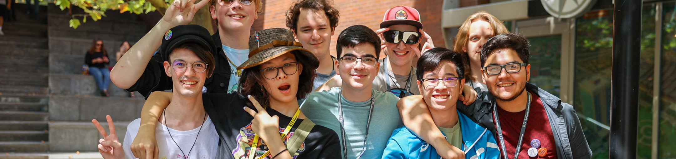 Students in a group smiling and making peace sign with hands