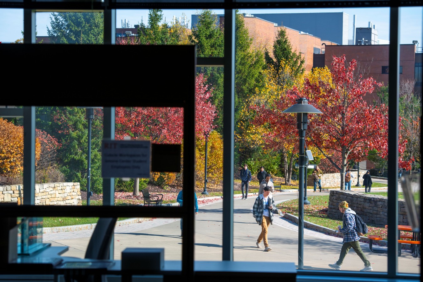 view of walking path between COS and GCCIS from inside GCCIS in the fall