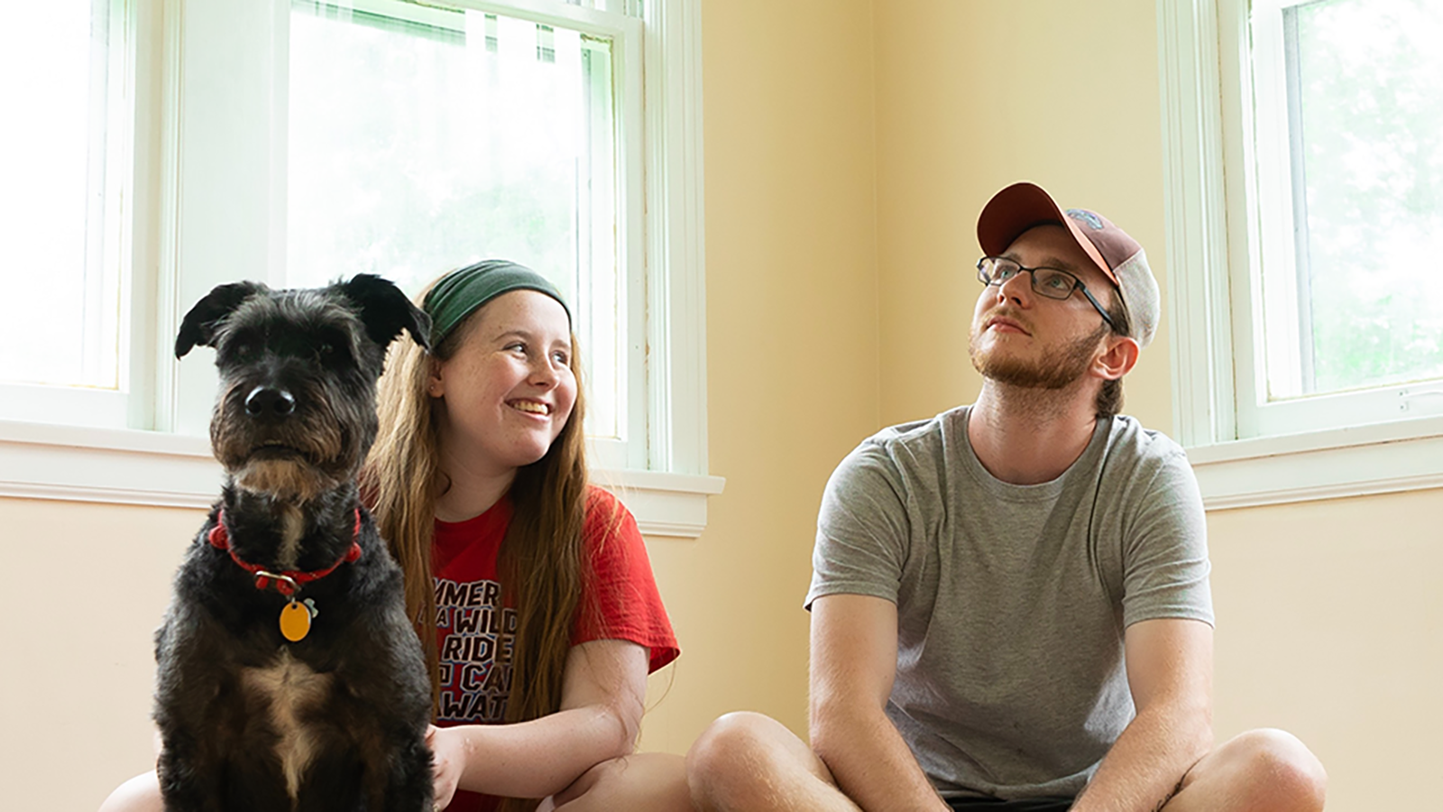 couple and their dog sitting in empty room in new house