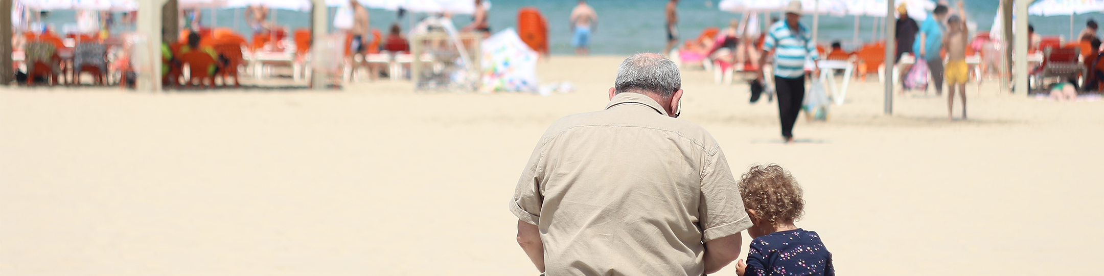 grandparent and child sitting together watching the beach in the background