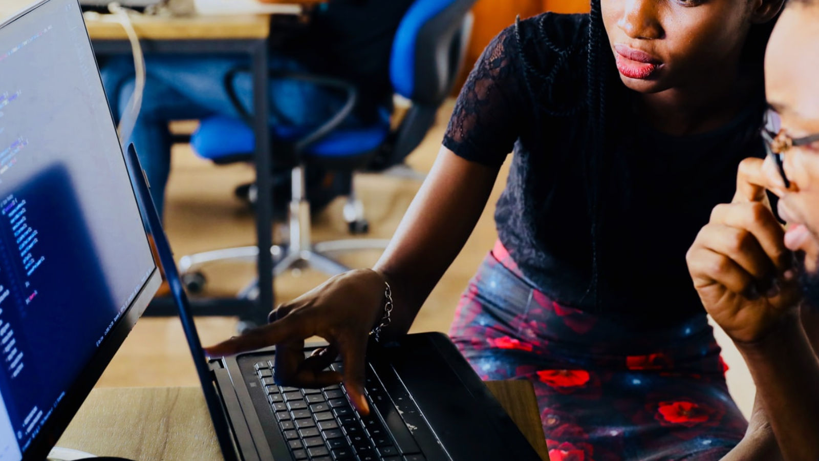 Two people working together on a dual screen computer