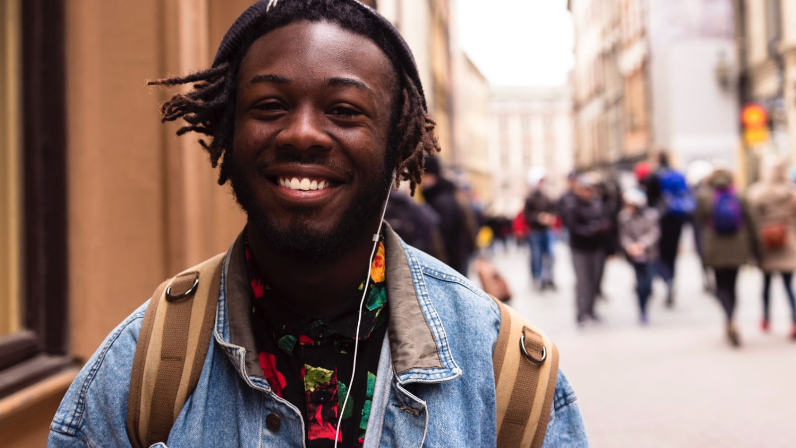 A man smiling on a college street with a group of students out of focus behind him