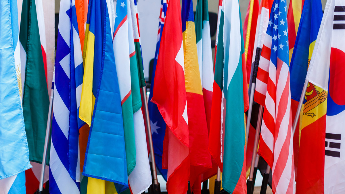 Close up of several different country flags on poles.