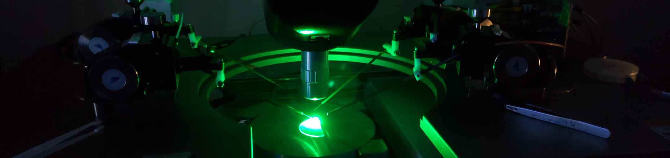 A glowing green light, with instruments in a lab setting.