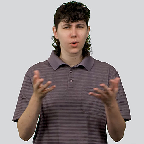 The image shows a person with short, curly dark hair and a mullet hairstyle. They are wearing a collared, short-sleeved, gray and purple striped shirt. The person is signing 'what,' conveying an expressive or questioning manner. The background is a plain light gray.