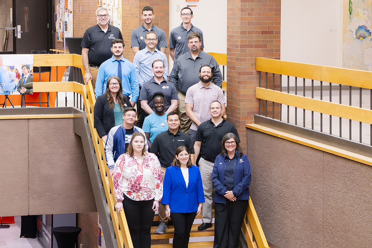 Alumni standing on the stairs inside the NTID LBJ building.